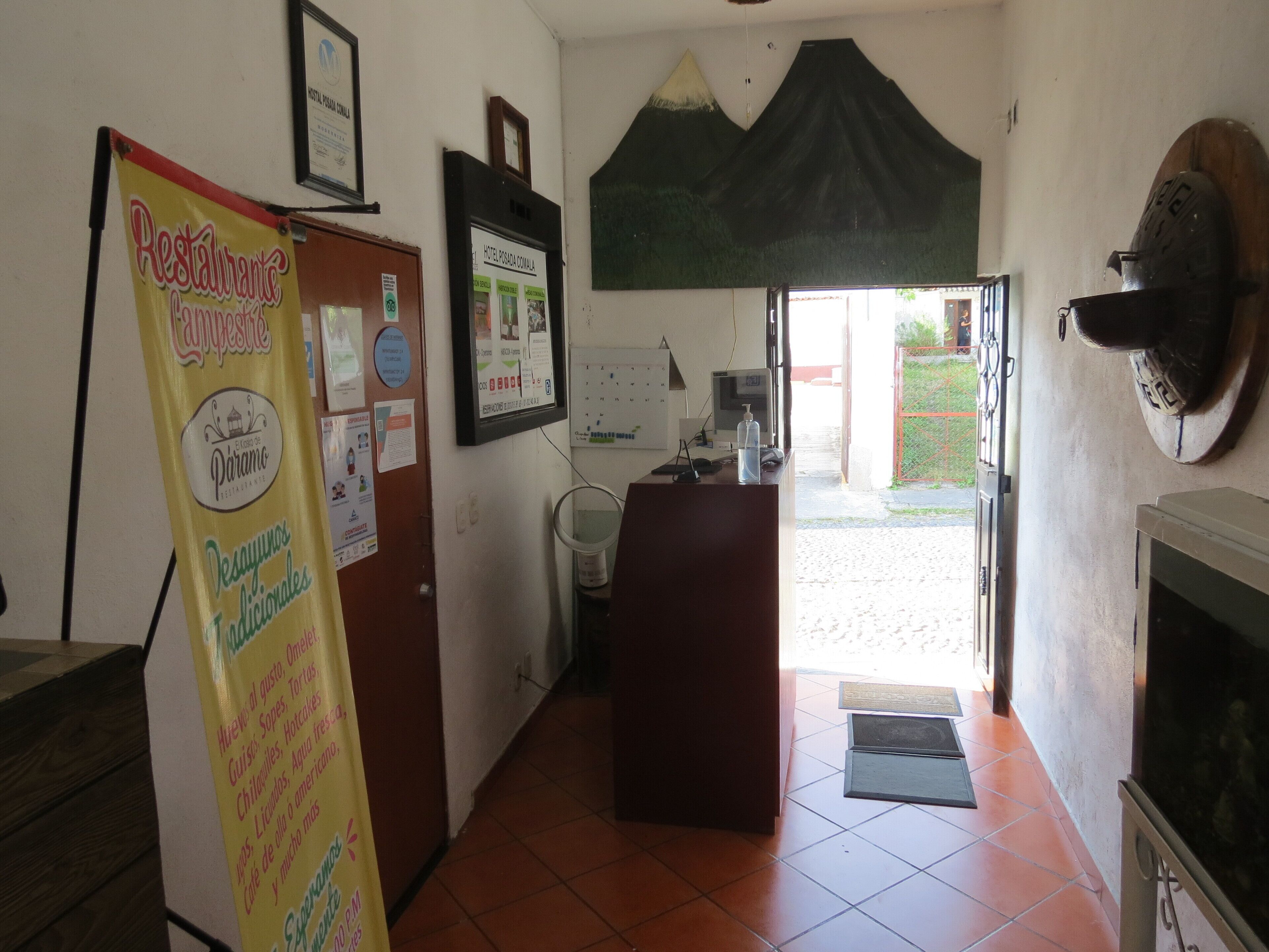 A reception area with a desk, a computer, and a large poster advertising traditional dishes.