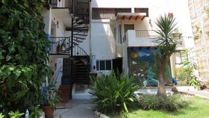 Un edificio moderno con una escalera de caracol, un mural y un pequeño jardín.