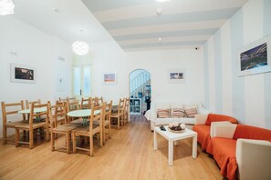 A spacious living area with a dining table, wooden chairs, a white sofa, and a red sofa. - Antas Ville Guesthouse (Porto)