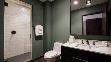 A modern bathroom with a white toilet, a glass shower enclosure, a white sink with a black vanity, and a mirror above the sink.