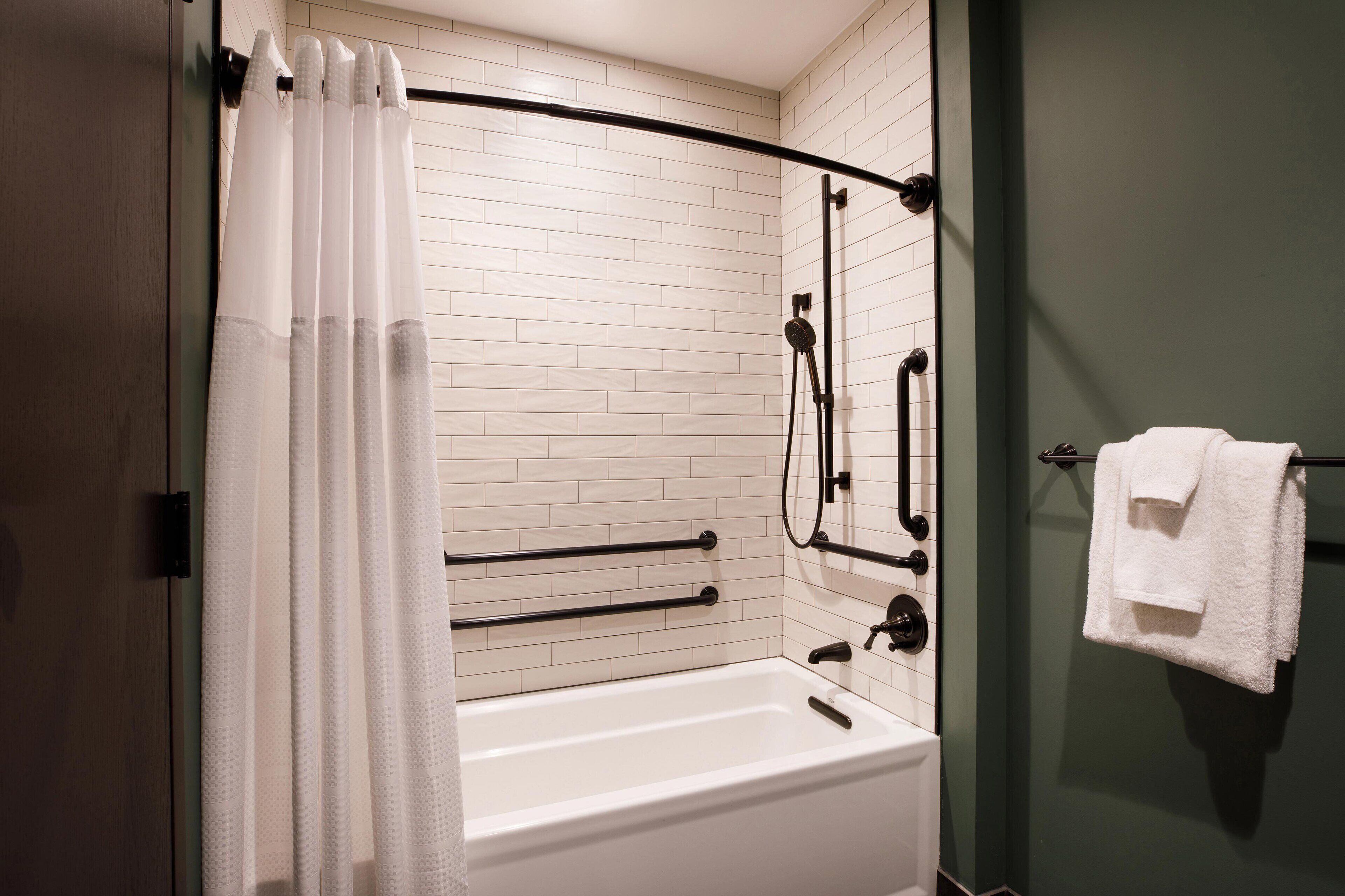 A modern bathroom with a white bathtub, a glass shower enclosure, and a towel rack.