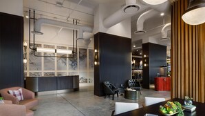 Eine moderne Lobby mit einer Rezeption, einer Sitzecke und einem Esstisch mit einer dekorativen Mittelstück.