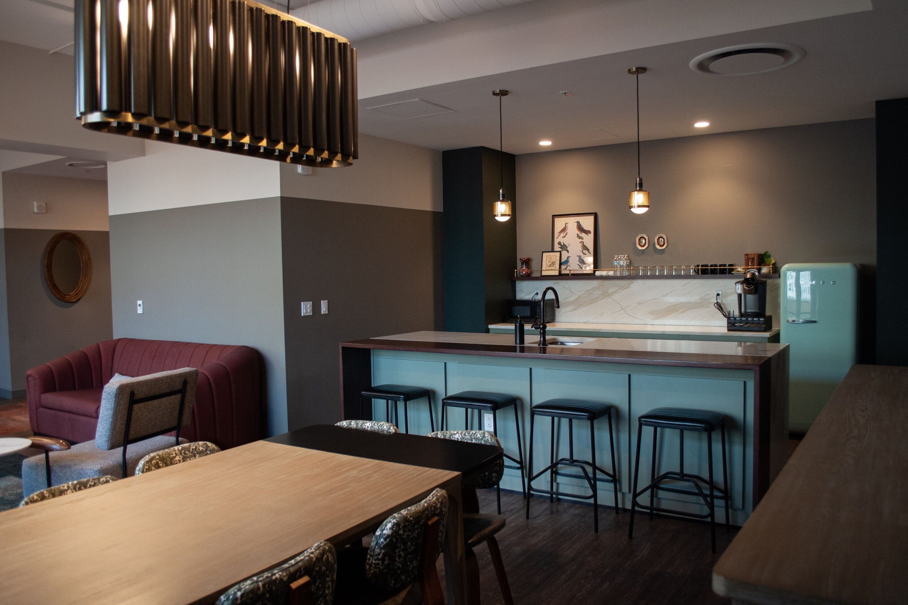 A modern kitchen with a central island, bar stools, and pendant lighting.