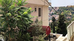 Un edificio residencial con balcón, una motocicleta estacionada y vistas de un pueblo montañoso.