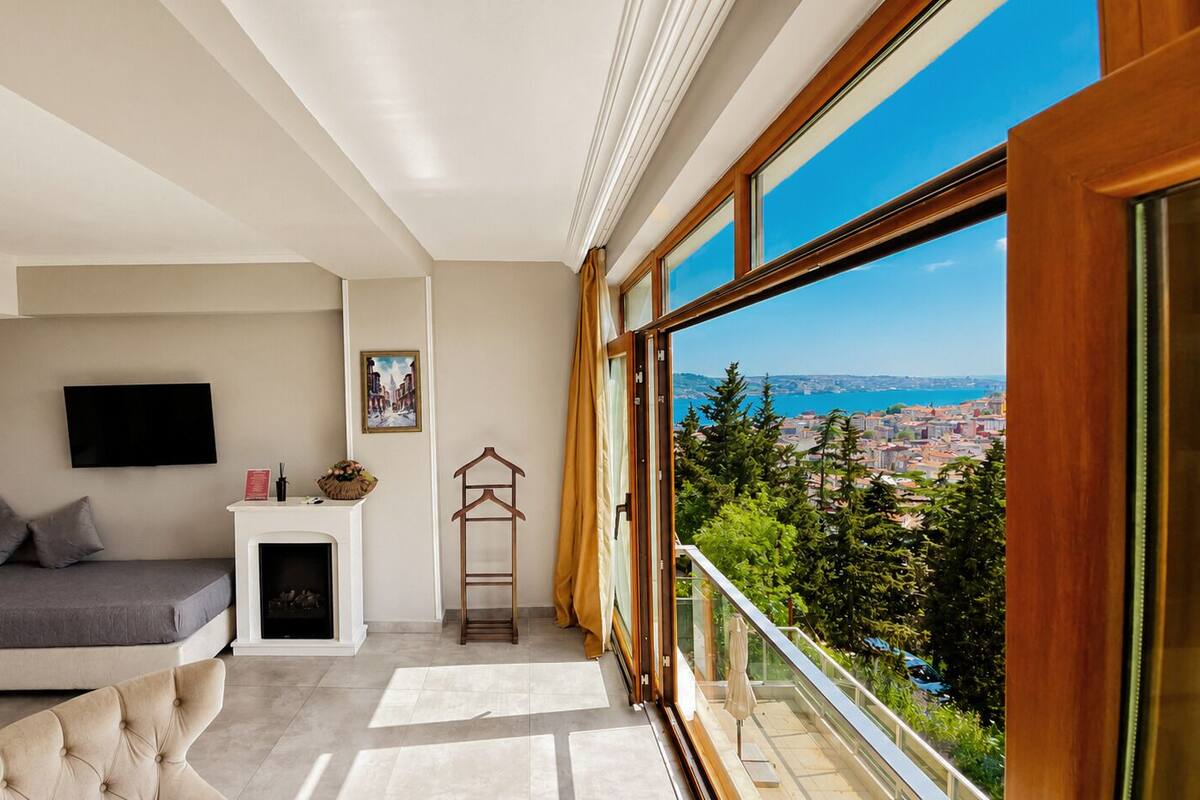 Quarto moderno com cama, televisão, lareira e varanda com vista para a cidade.