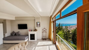 Une chambre moderne équipée d’un lit, d’une télévision, d’une cheminée et d’un balcon offrant une vue sur la ville.