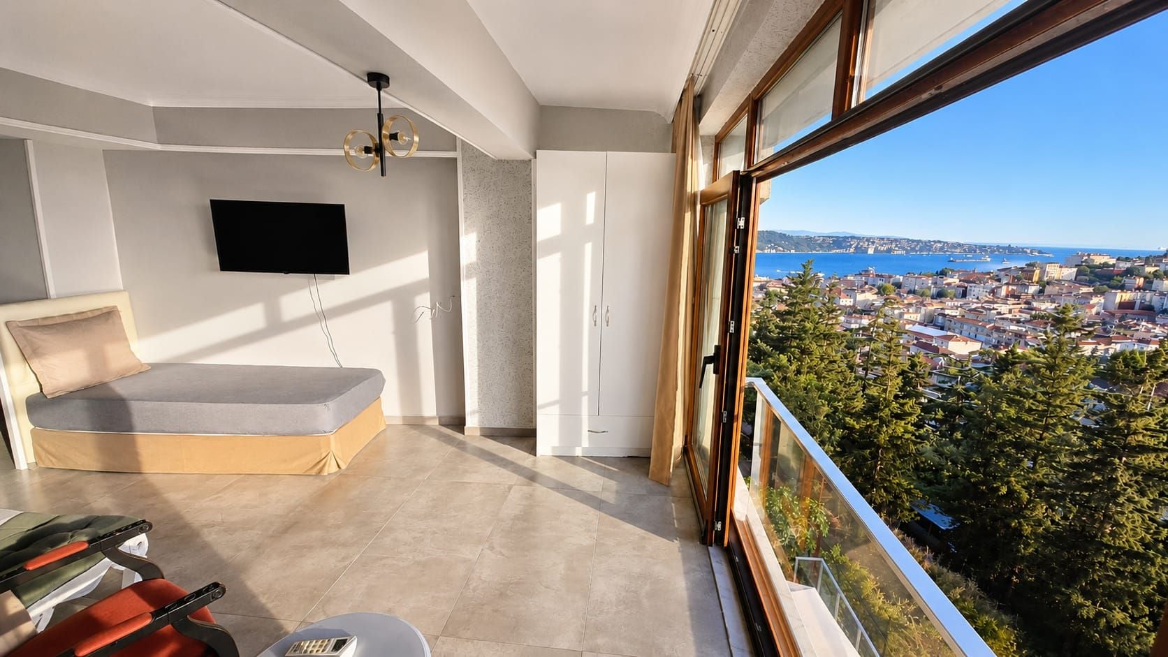 A balcony with a city view, a sofa, a TV, and a ceiling light fixture.