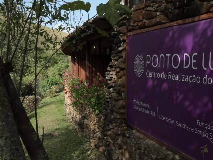 A sign for "Ponto de Luz Centro de Realização do Ser" with a logo, establishment date, and founders' names.