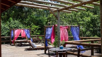 A wooden deck with a table and chairs, surrounded by a bamboo fence.