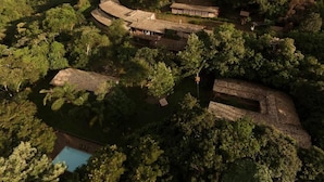 Eine Vogelperspektive auf einen traditionellen Gebäudekomplex, umgeben von dichtem Wald, mit einem Schwimmbecken im Vordergrund.