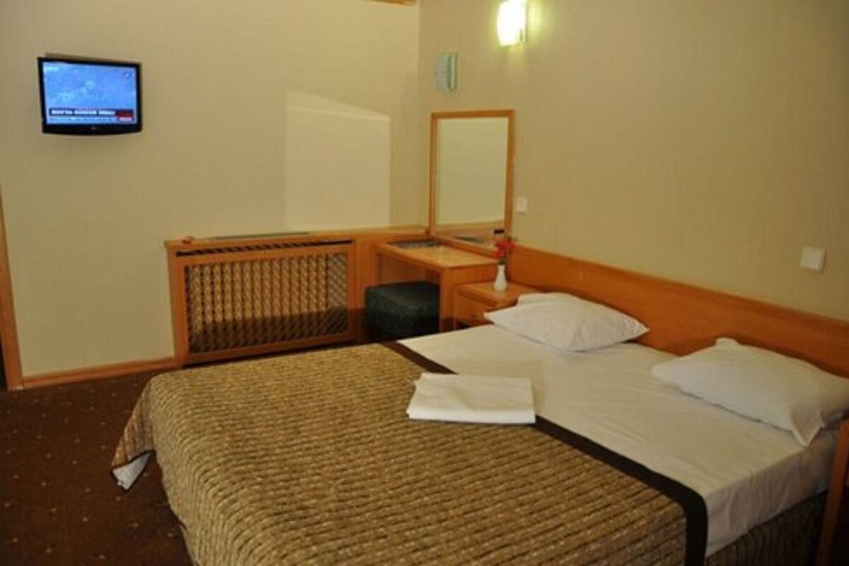 Una habitación de hotel con cama, televisión, una mesita y un espejo.