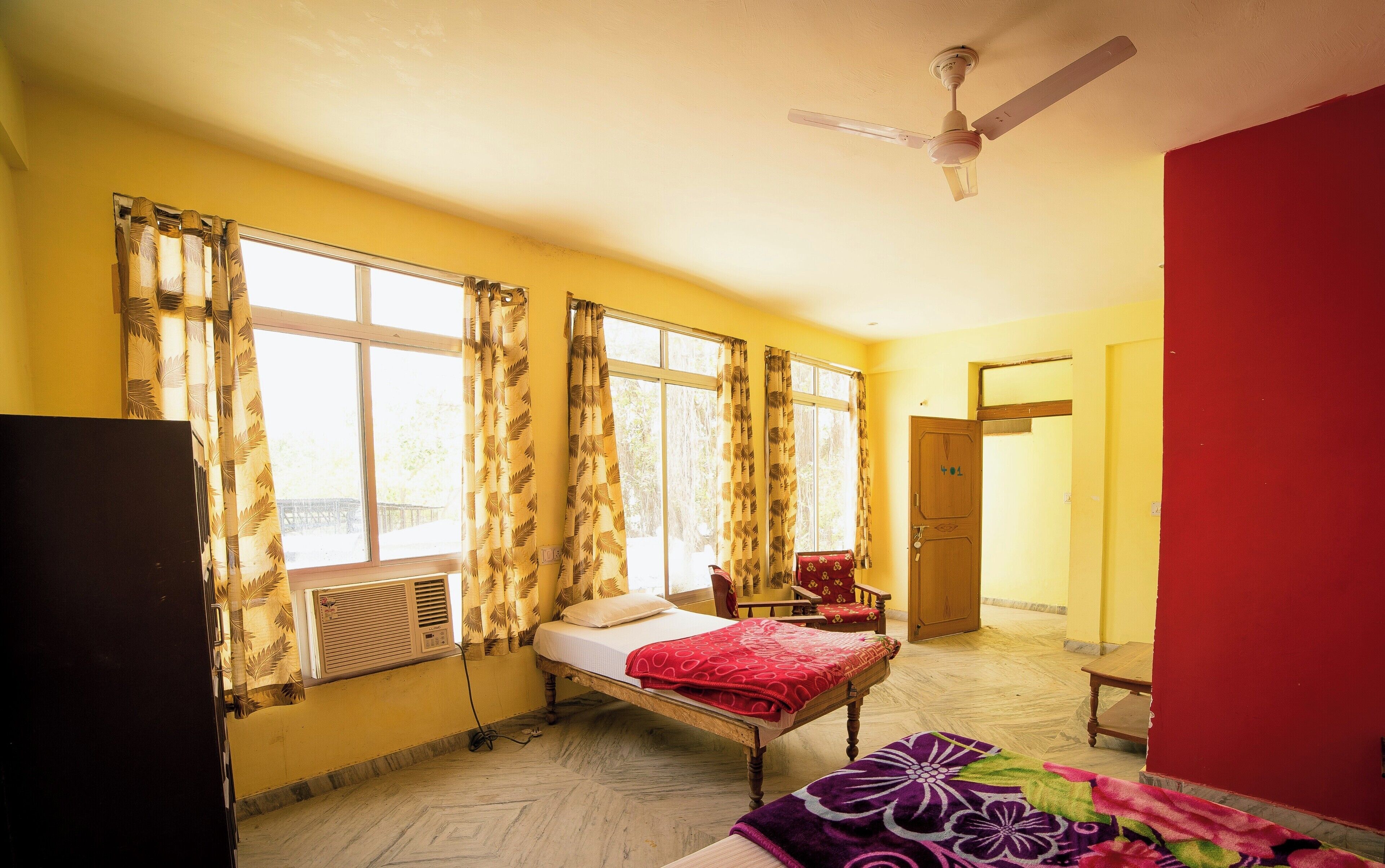 A room with a bed, a chair, a desk, and a window with curtains.