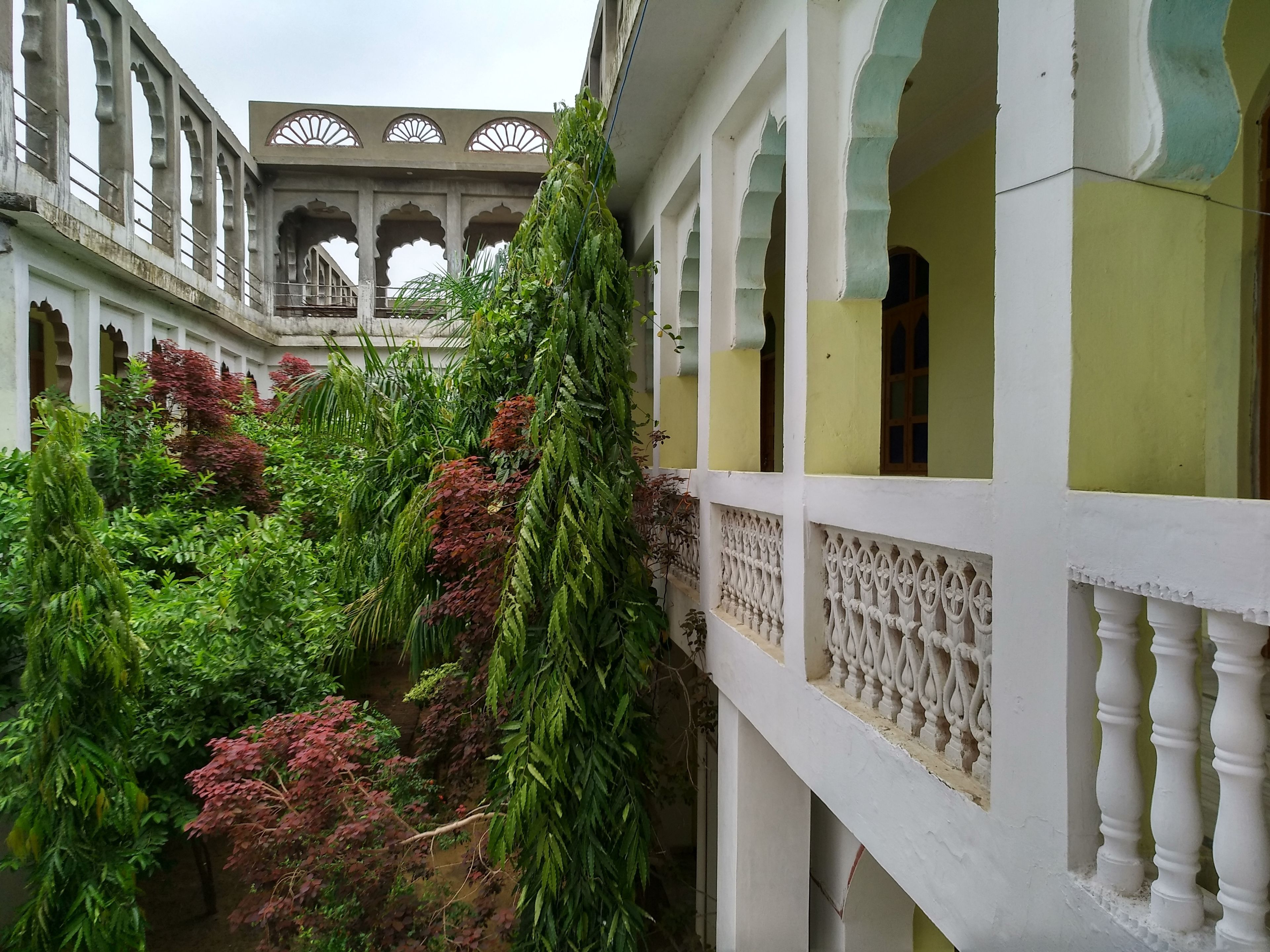 Un patio con un edificio blanco que presenta arcos y un balcón.