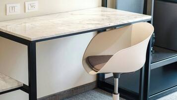 Un escritorio moderno con cubierta de mármol blanco, estructura metálica negra y una silla de oficina blanca con respaldo curvado.