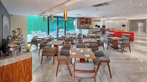 A modern restaurant with marble flooring, wooden tables and chairs, and a bright interior with natural light. - SJ Grand Hotel Monterrey (Monterrey)