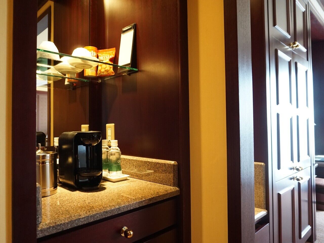 A hotel bathroom with a coffee maker, toiletries, and a mirror.