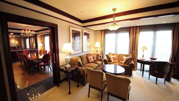 A hotel room with a dining area, a sofa set, a chandelier, and a large mirror.