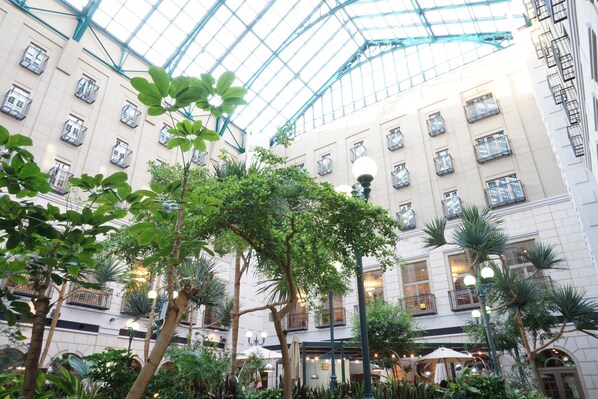 A spacious indoor atrium with a high glass ceiling, multiple balconies, and lush greenery. - Mito Plaza Hotel (Mito)
