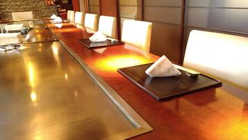 A long, polished wooden reception desk with a glass partition, a stone wall, and a modern interior design.