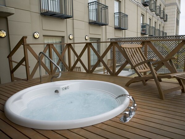 A hot tub on a wooden deck with a railing and chairs. - Mito Plaza Hotel (Mito)