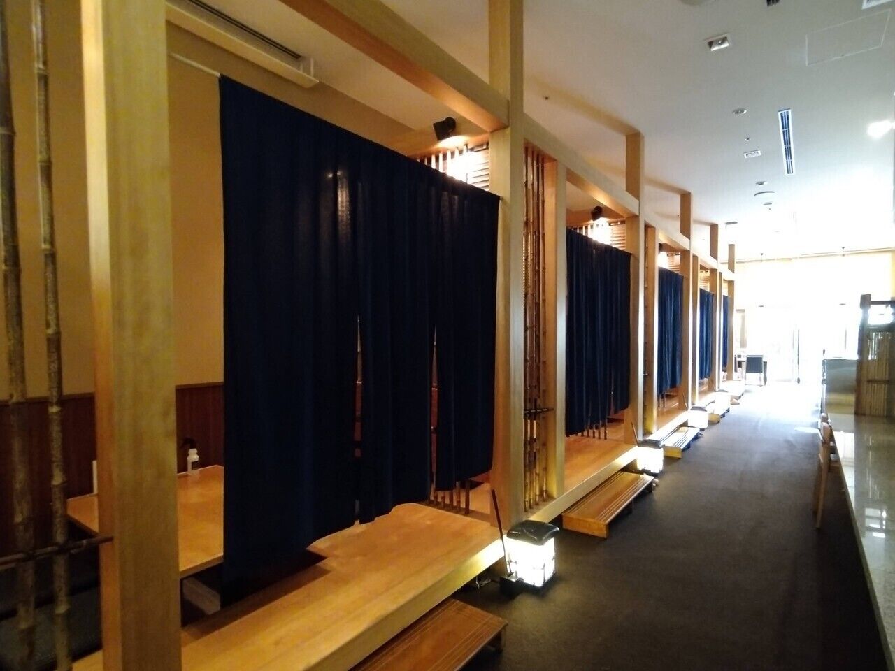 A row of wooden benches with dark curtains, a wooden floor, and a bright ceiling.
