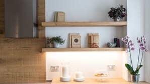 Une cuisine moderne dotée d’un plan de travail en bois, d’étagères intégrées et d’une hotte de cuisine en acier inoxydable.