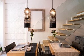 Un espace repas avec une table en bois, des bancs et des lampes suspendues.