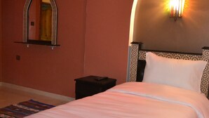 Una cama bien hecha con un cabecero decorativo, una mesita de noche y un espejo instalado en la pared.