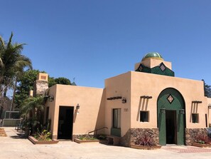 Un edificio con una cúpula verde y fachada color beige, que presenta una entrada de piedra y el número 5585 en la pared.