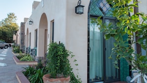 A row of buildings with arched windows and a row of potted plants in front. - Casa Del Sol (Carpinteria)