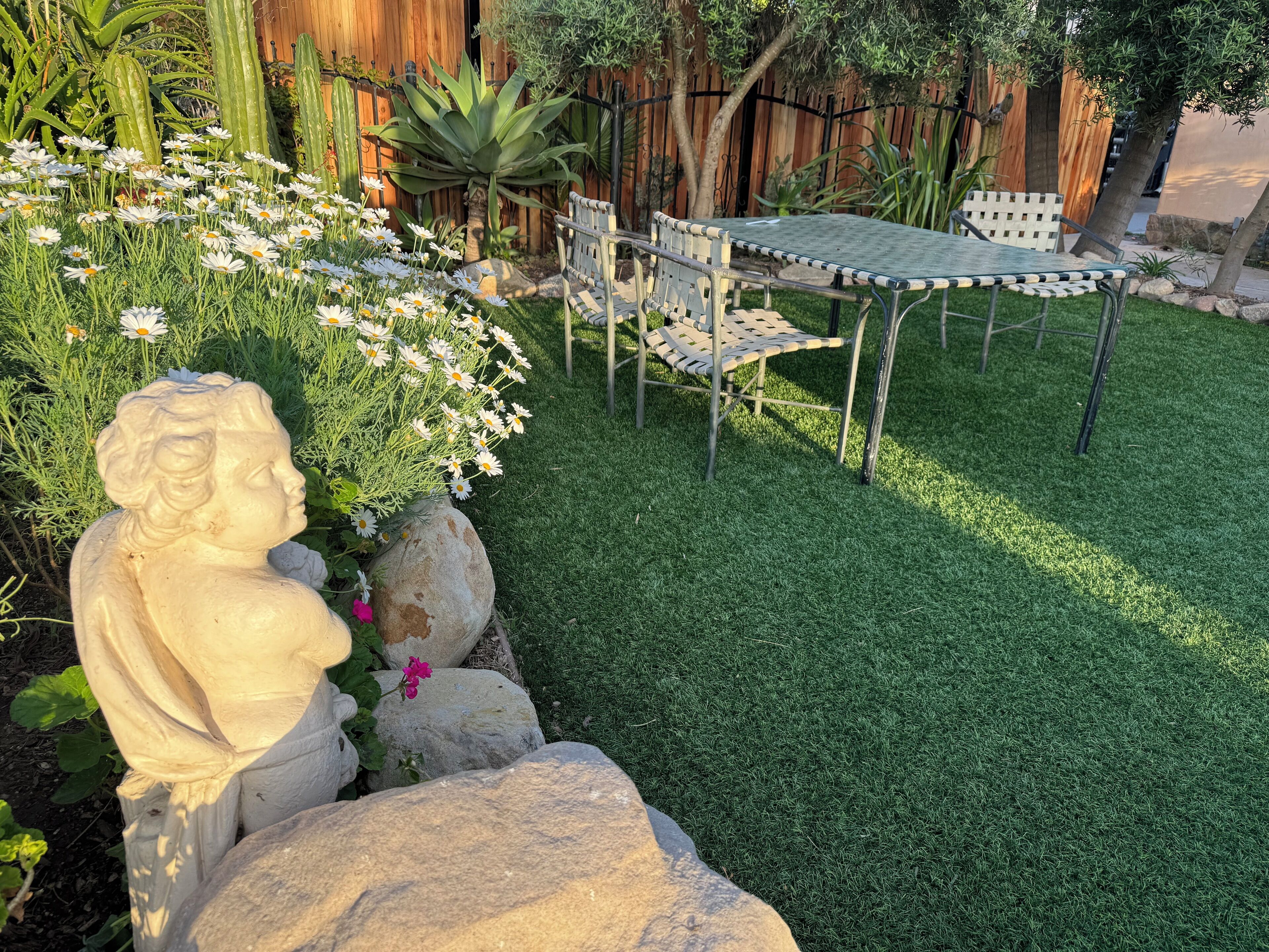 A garden with a statue, a table, and chairs.