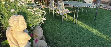 A garden with a statue, a table, and chairs.