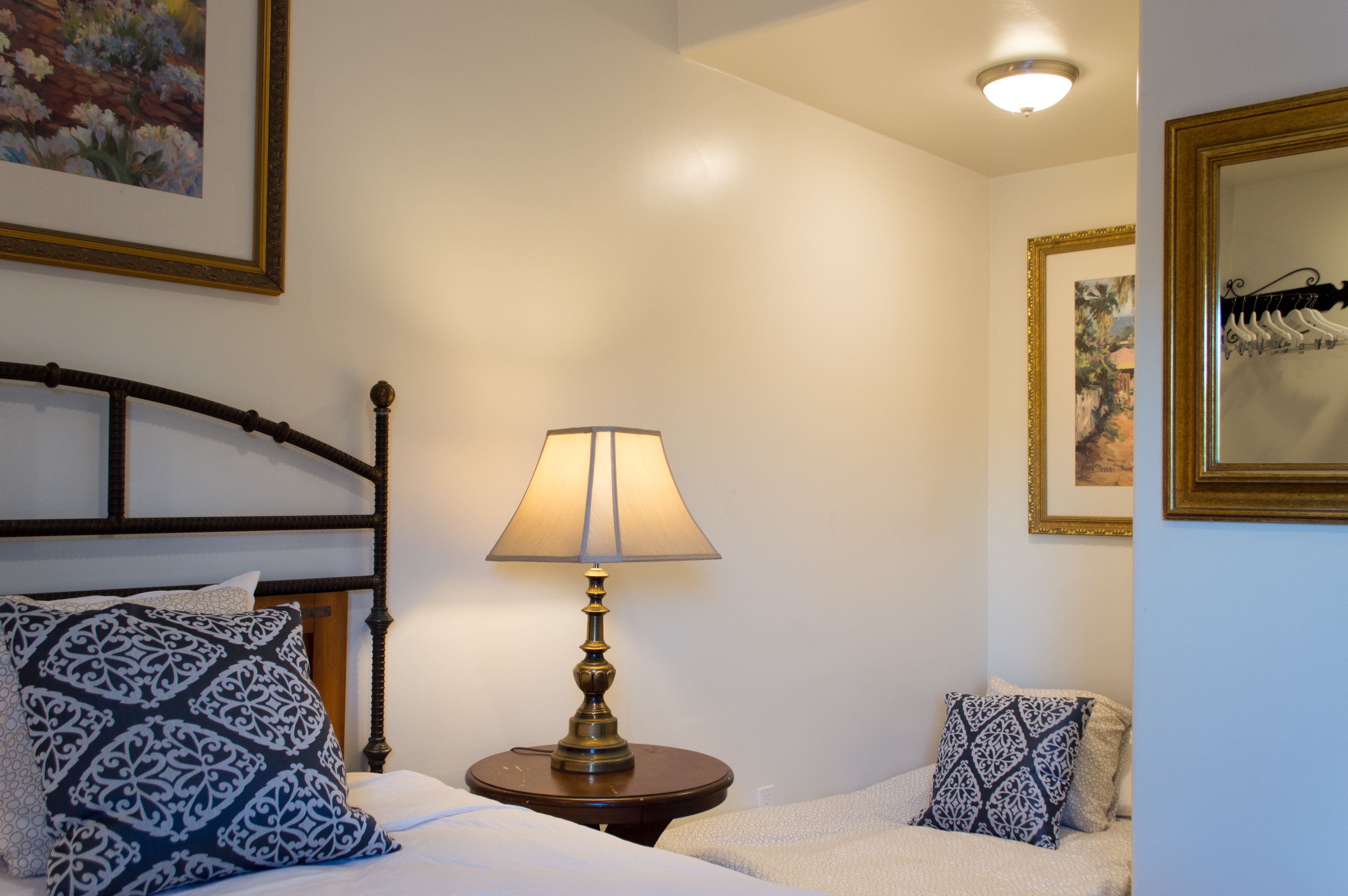 A neatly made bed with patterned pillows, a bedside lamp, and framed artwork on the walls.