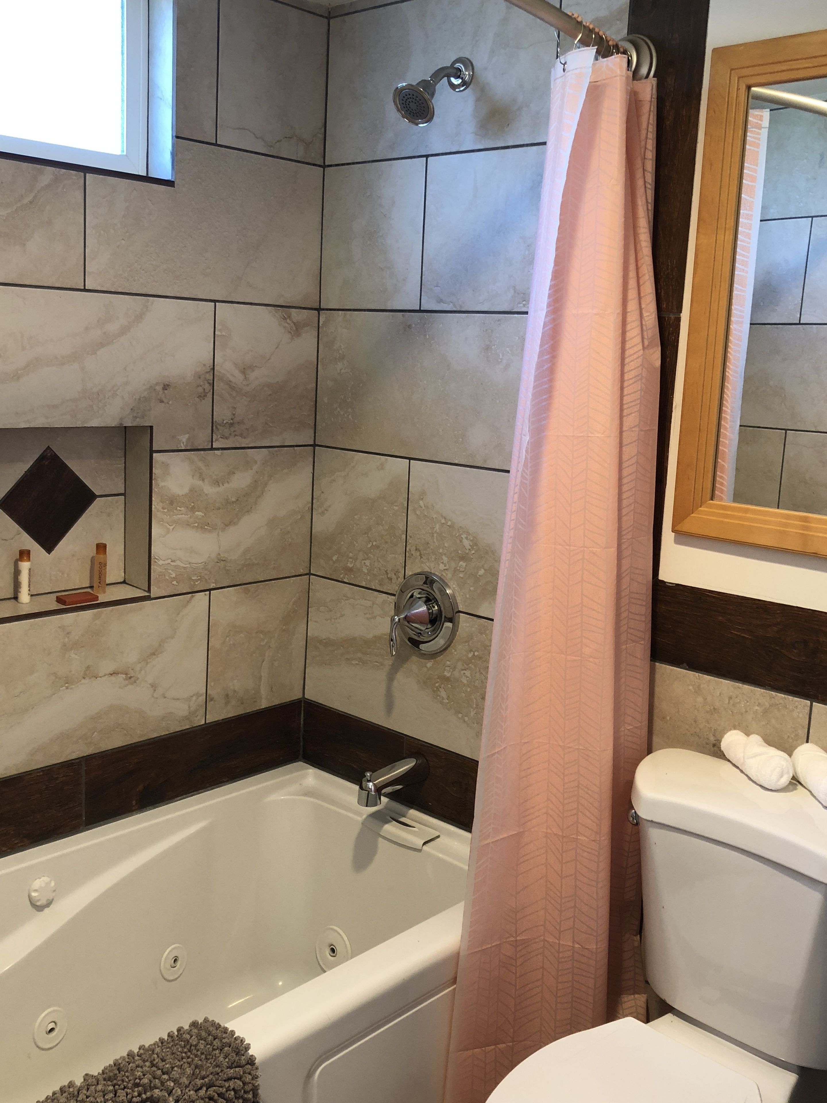 A bathroom with a bathtub, toilet, and a shower curtain.