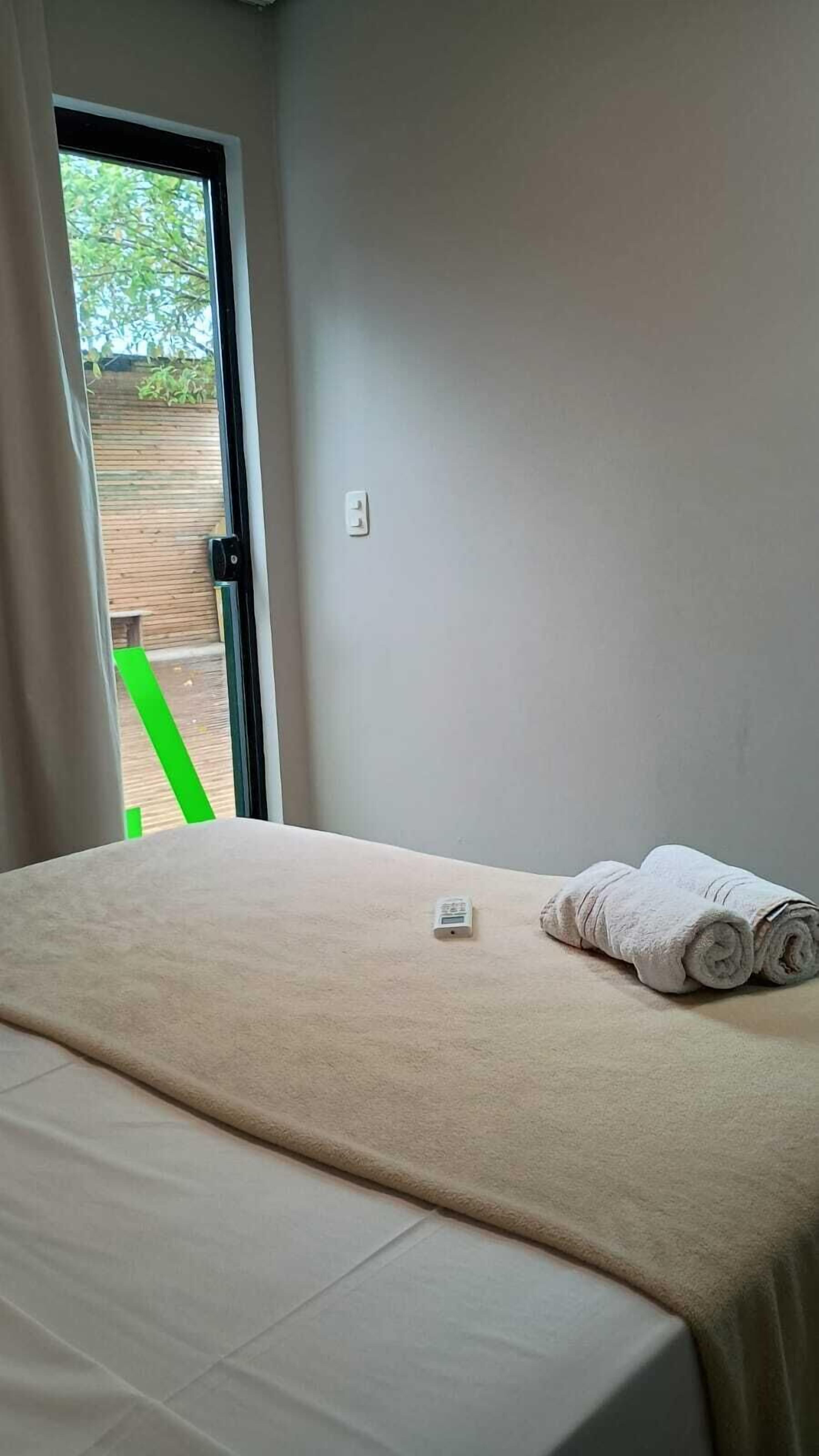 A bedroom with a bed, a window, and a view of the outside.