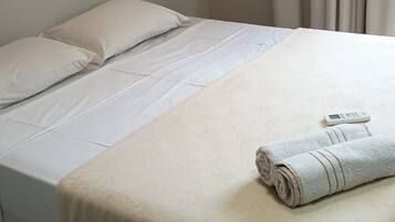 A single bed with white bedding and a folded towel on the footboard.