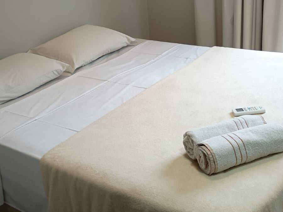 A single bed with white bedding and a folded towel on the footboard.