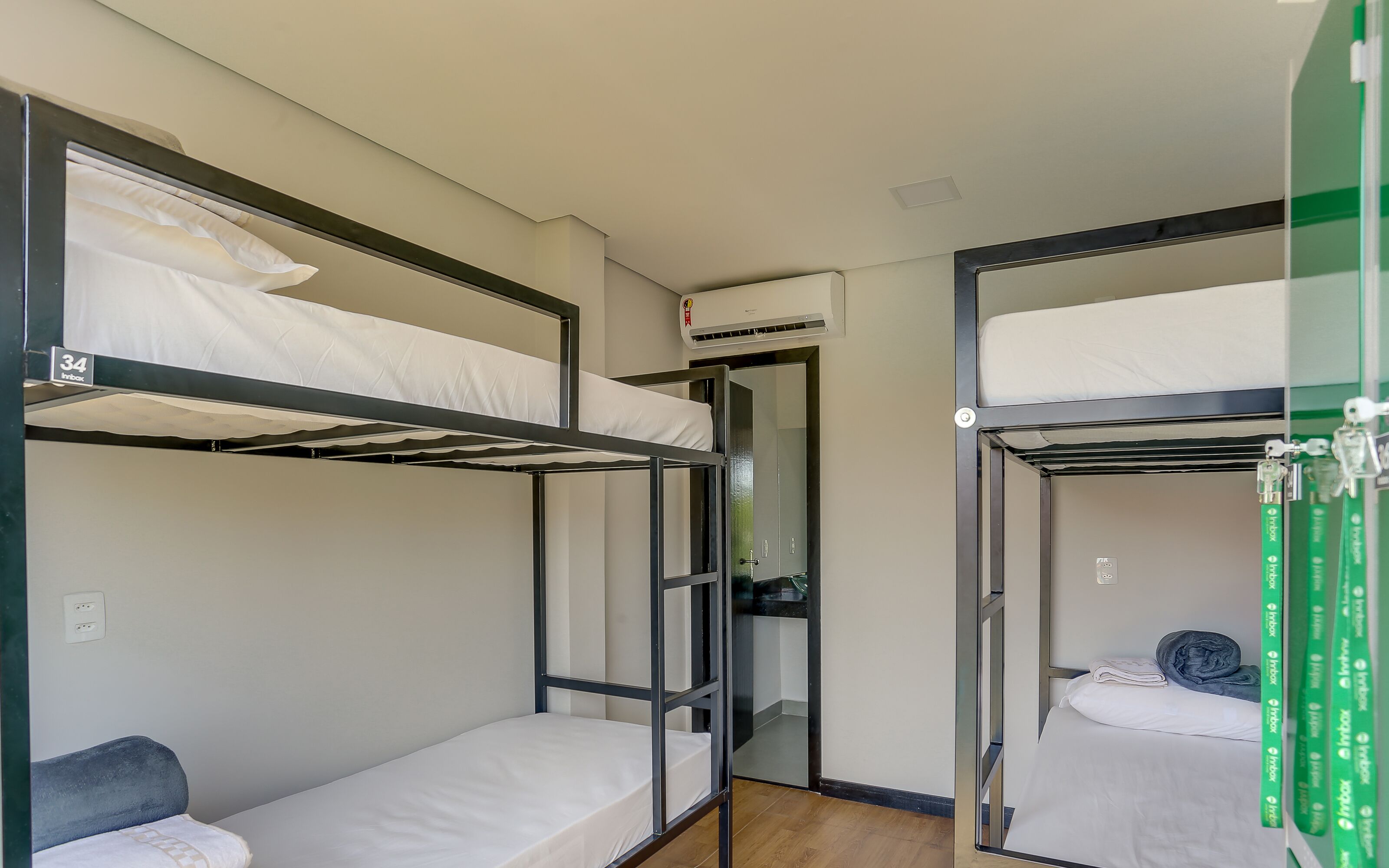 A dormitory room with bunk beds, a small kitchenette, and a door leading to a bathroom.