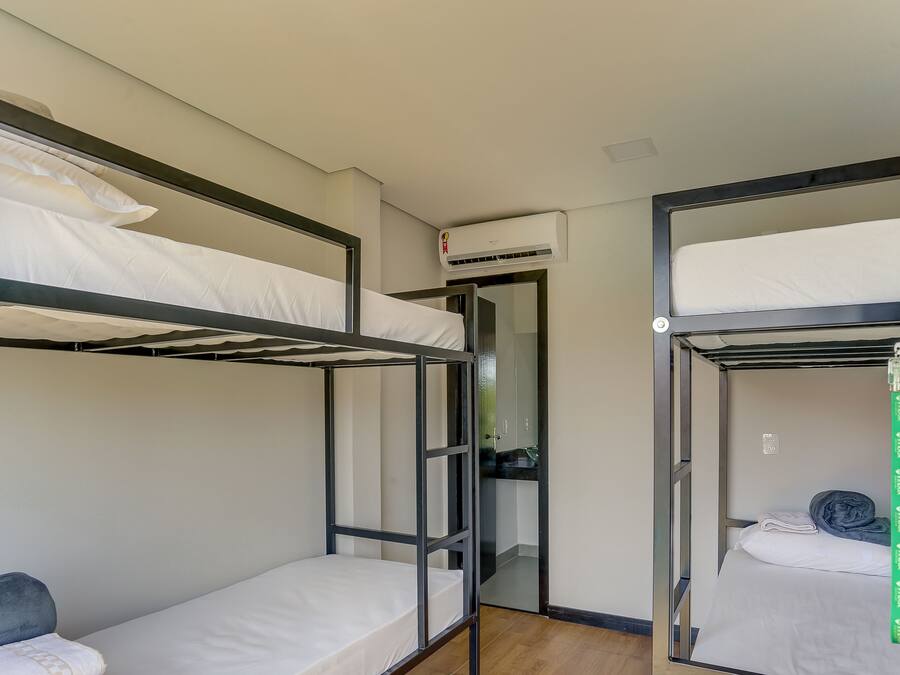 A dormitory room with bunk beds, a small kitchenette, and a door leading to a bathroom.