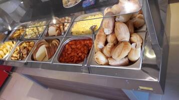 A buffet with various food items including bread, pastries, and a tray of carrots.