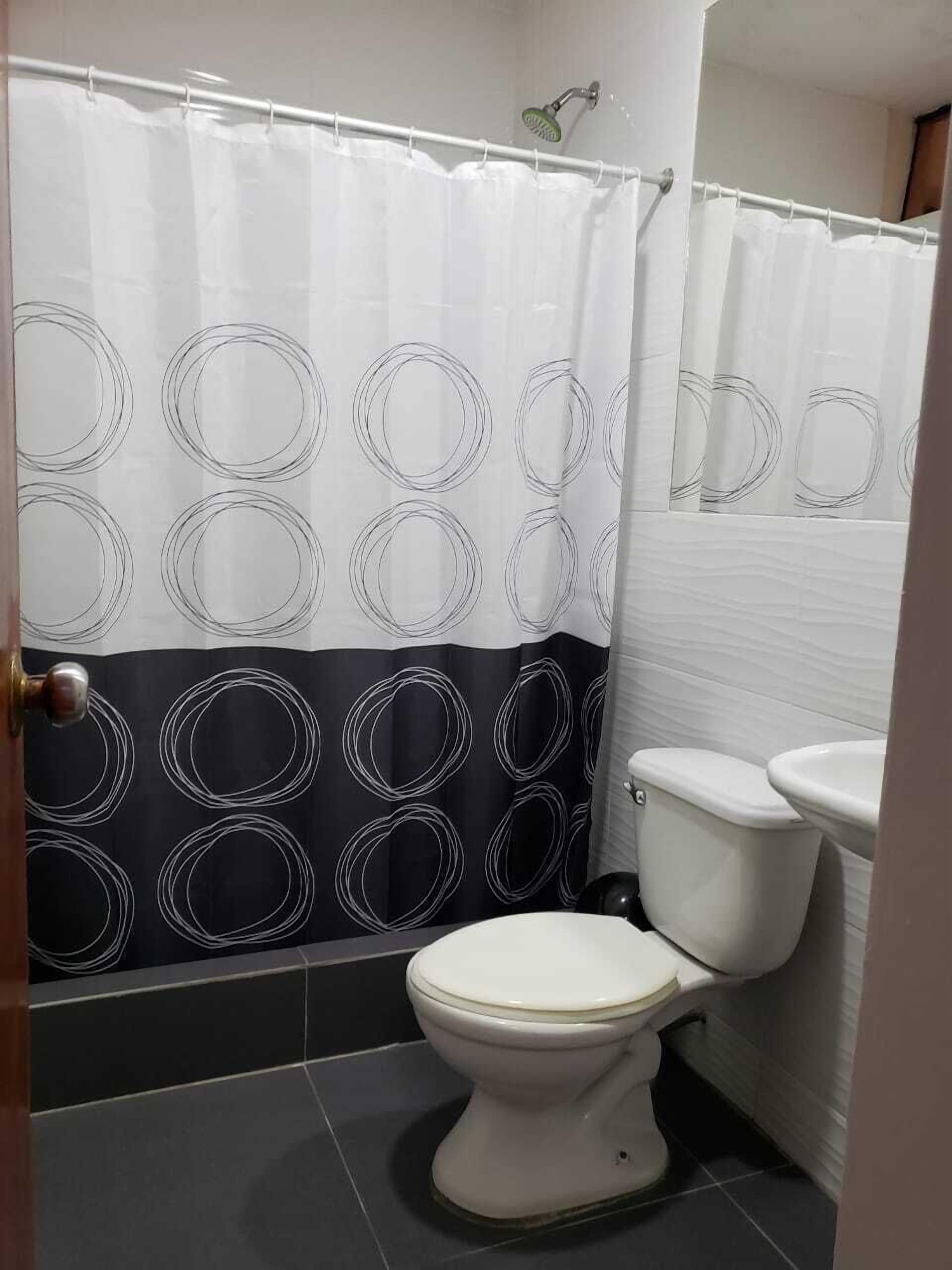 A bathroom with a toilet, a sink, and a shower curtain with a circular pattern.