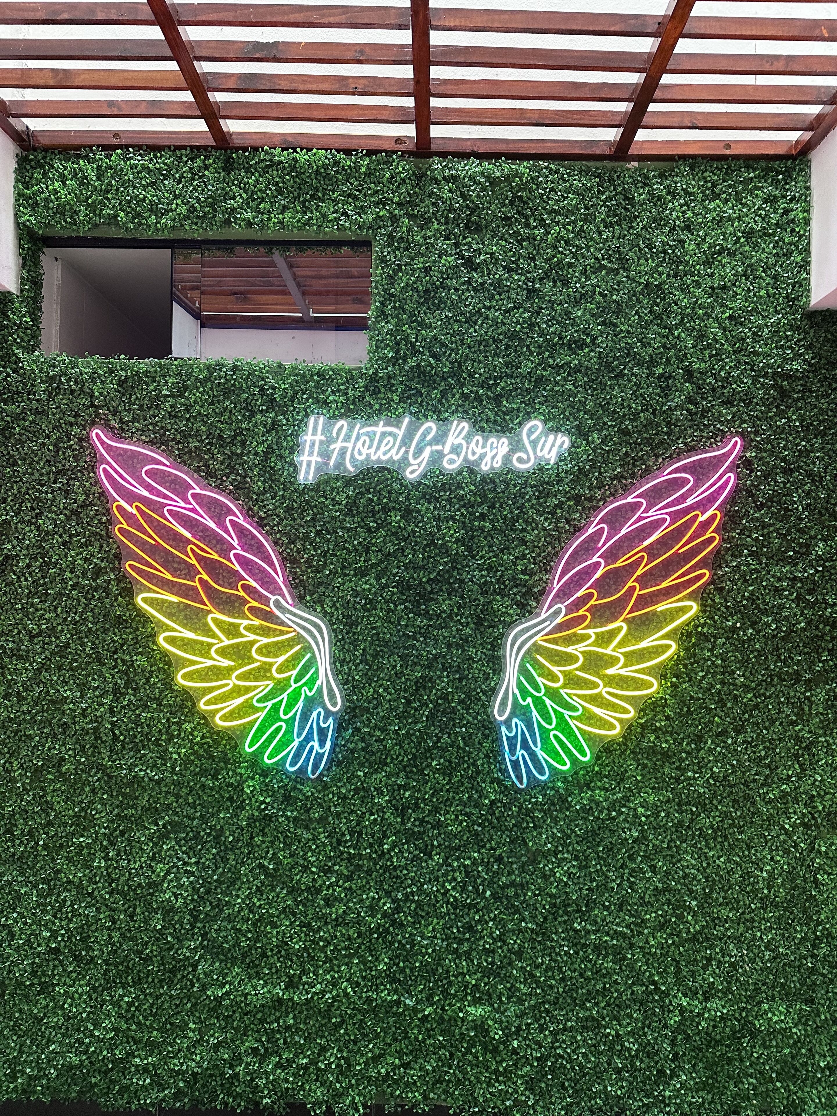 A wall with a neon sign reading "#Hotel G-Boss Sun" and two neon wings.