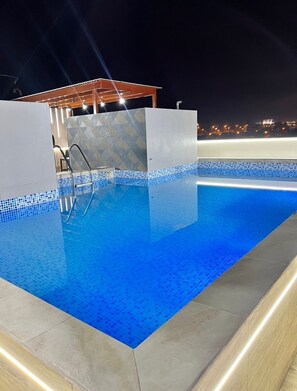 A rectangular swimming pool with a tiled edge and a metal ladder leading into the water. - G-Boss Hotel Sur (Lurín)