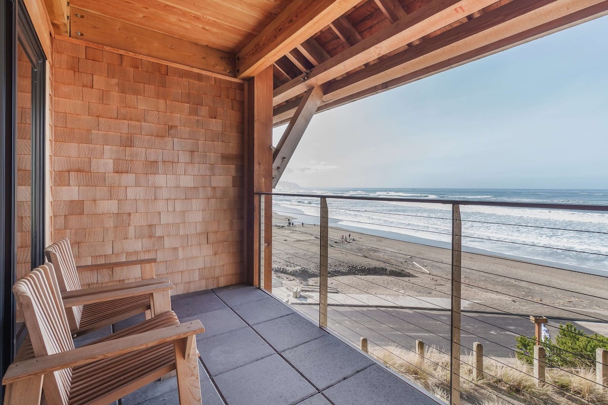 Un balcon avec un banc en bois, un mur en briques et une vue sur la plage.