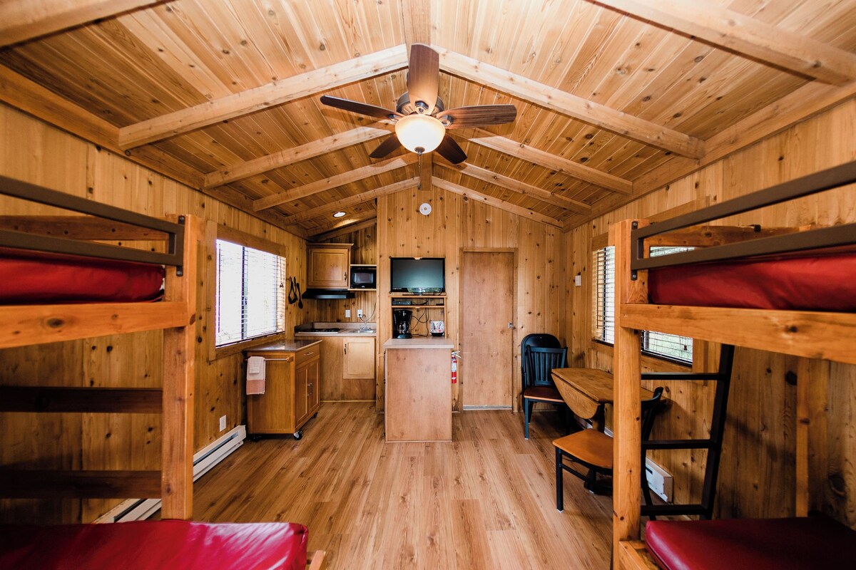 L’intérieur d’une cabine comprend des lits superposés, un coin cuisine et un ventilateur de plafond.
