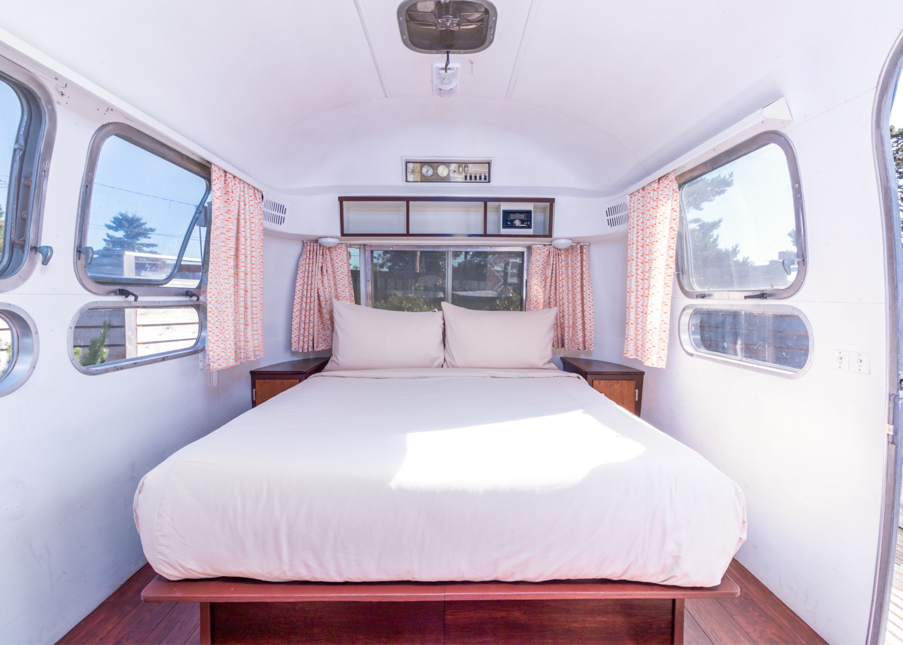 A bedroom with a bed, curtains, a window, and a control panel.