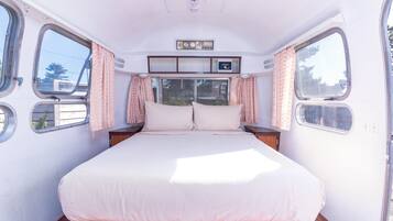 Quarto com cama, cortinas, janela e painel de controle.