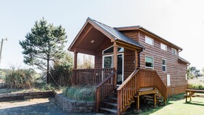Een houten hutje met een veranda, een trap en een picknicktafel.