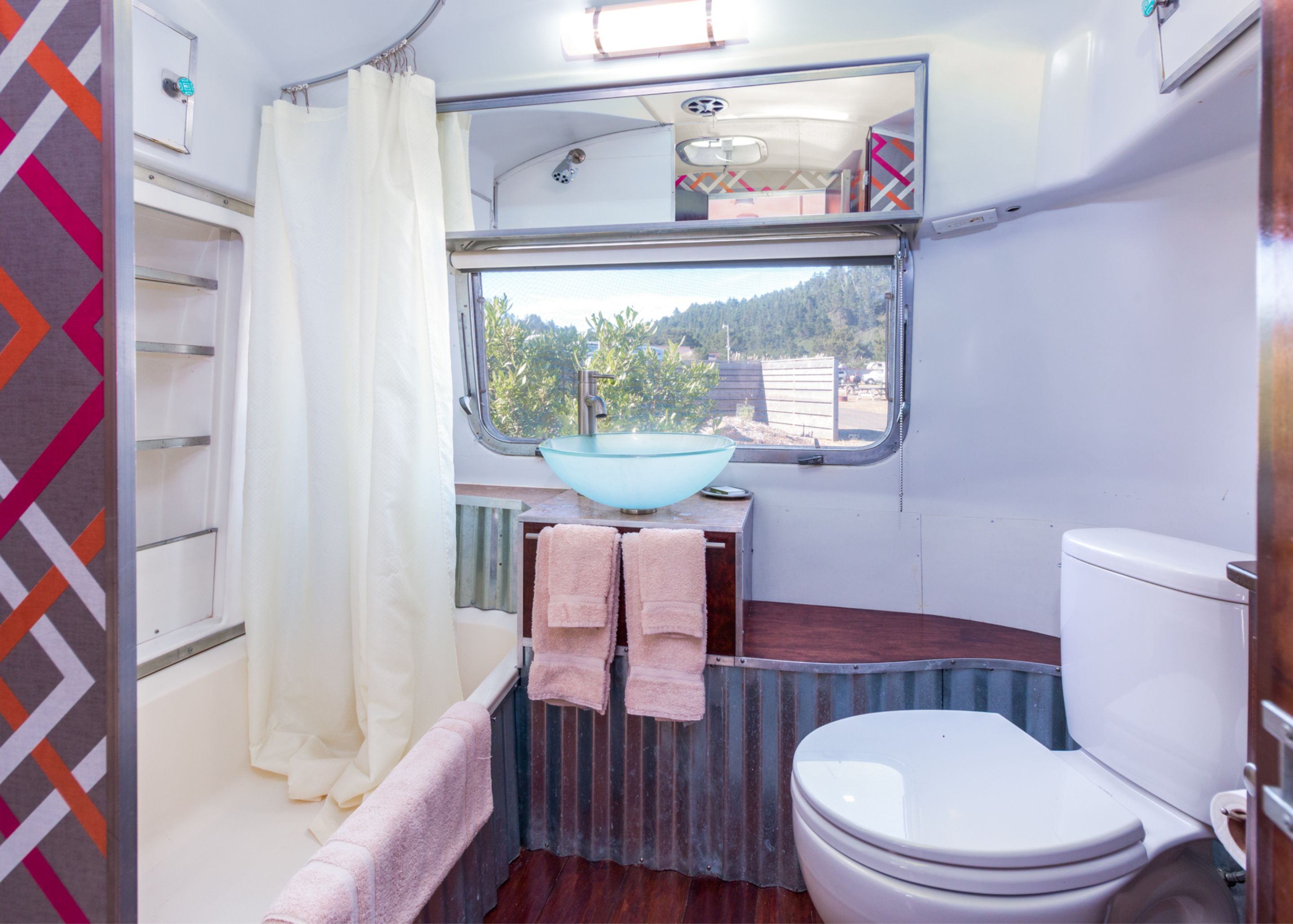 Une petite salle de bain comprenant des toilettes, un lavabo avec une fenêtre au-dessus et un espace douche.