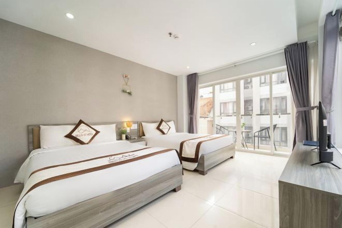 A hotel room with two beds, a TV, a balcony with a view, and a modern design.